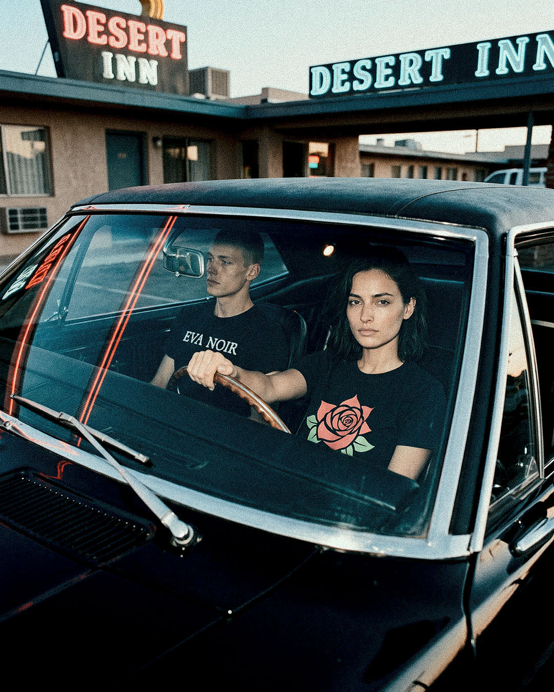 Two travelers outside a desert inn in Eva Noir graphic T-shirts